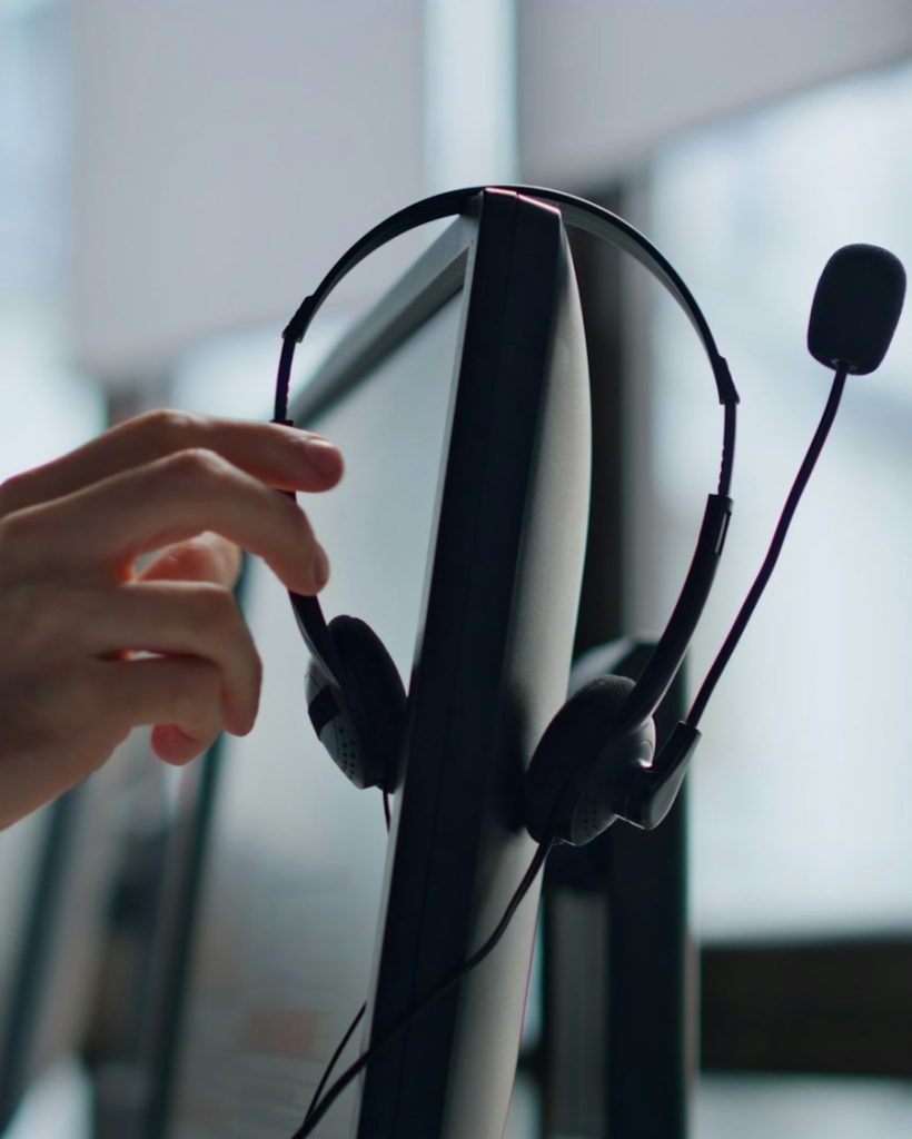 Closeup hand taking headset at call center. Technical support equipment hanging