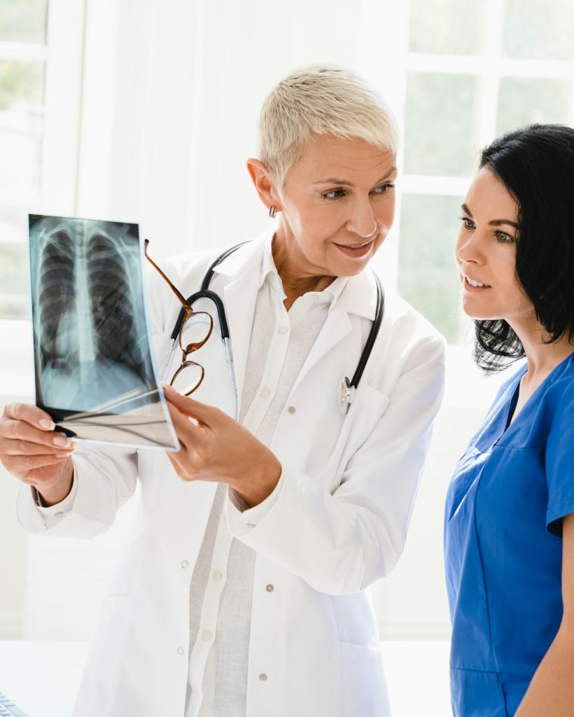 Doctor showing x-ray image of lungs to medical student intern nurse, explaining illness diagnosis